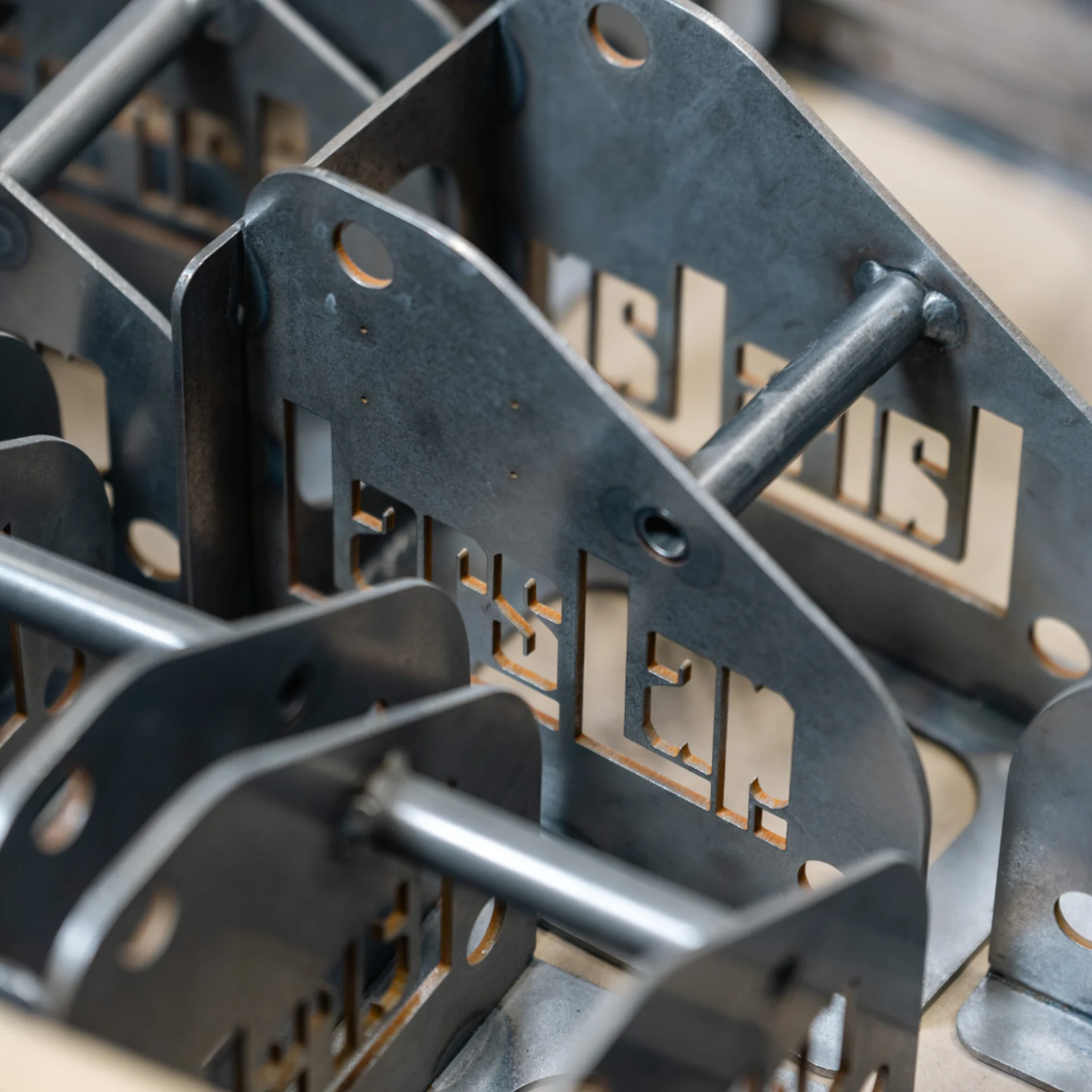 Close-up of several metal brackets with rods passing through them, featuring precise cut-out shapes and holes, arranged in a neat, organized manner.