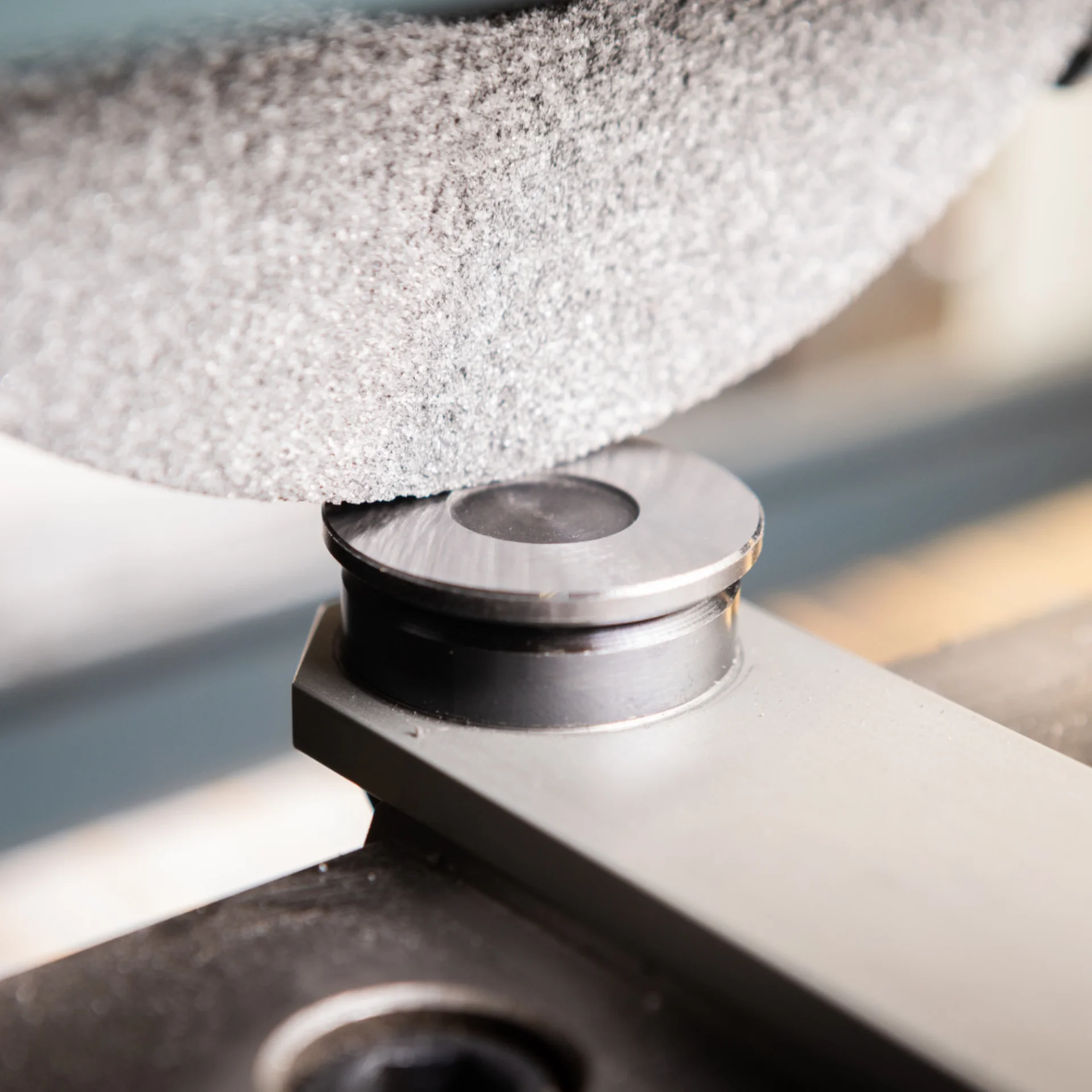 A close-up of a circular grinding wheel polishing a metal part on a machine, with visible sparks and smooth surface finish.